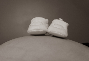 Des chaussons de nourissons sur le ventre d'une femme